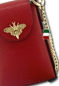 Rode leren handtas met een gestructureerd oppervlak, goudkleurig bijenembleem en gouden schouderband. Voorzien van een klein Italië-vlag charm.