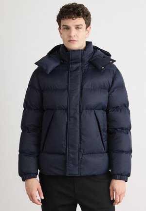 Veste matelassée bleu marine avec un col haut, tissu texturé, fermeture éclair à l'avant et deux poches avant ; poignets élastiques ; design à capuche.