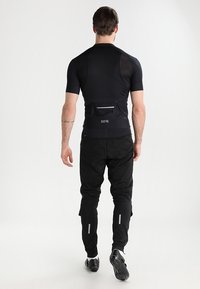 Conjunto deportivo negro para hombre que incluye una camiseta ajustada de manga corta y pantalones entallados con detalles reflectantes; tela suave y práctico bolsillo trasero.