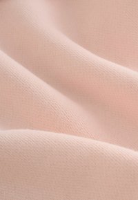 Šviesiai rožinė medžiaga, turinti švelnų, lygaus paviršiaus tekstūrą, rodanti švelnias raukšles ir smulkų, tolygų mezginį. Puikiai tinka drabužiams ar baldų apmušalams.