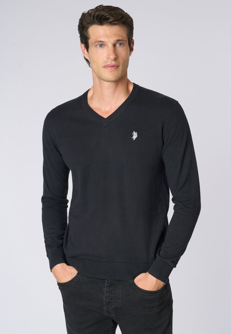 Maglione nero a V realizzato in un materiale a maglia liscia, con maniche lunghe, polsini e orlo a coste, e un piccolo logo ricamato sul petto.