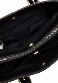 Sort læderhåndtaske indvendigt med flere rum, inklusive lynlåslommer og trykknapslukninger, med guldfarvet hardware.