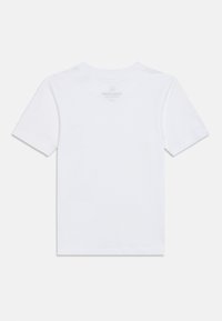 Λευκό βαμβακερό μπλουζάκι με στρογγυλή λαιμόκοψη και κοντά μανίκια. Η πίσω όψη δείχνει ελάχιστες ραφές και το λογότυπο εκτυπωμένο σε ανοιχτό γκρι.