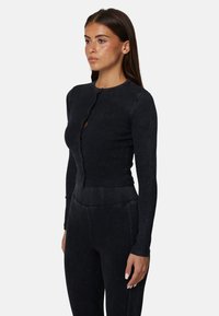 Czarny, prążkowany krótki top z długim rękawem, okrągłym dekoltem i zapięciem na guziki, z subtelnym logo na piersi i teksturowanym wykończeniem.