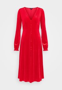 Röd sammet klänning med långa ärmar, V-ringning och en rad knappar nedtill. Slät textur, utställd fåll och draperade ärmslut.