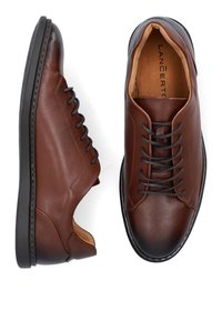 Brązowe skórzane buty na sznurowadła o gładkiej fakturze, zaokrąglonym nosku i czarnej gumowej podeszwie. Posiadają kontrastowe przeszycia i minimalne akcenty.