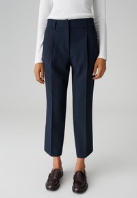Pantaloni eleganti navy con vita alta, gamba dritta e piega stirata. Realizzati in un tessuto morbido, abbinati a mocassini in pelle scura.