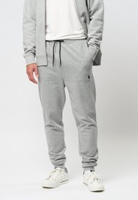 Graue Sweatpants aus Baumwollmischung mit elastischem Bund und Kordelzug, schmal zulaufenden Beinen und Logodetail am linken Oberschenkel.