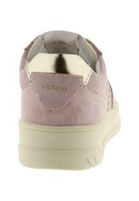 Roze suède sneaker met crèmekleurige zool, gouden metalen hielstuk en "victoria" merk op de achterkant, gezien vanuit de achterkant.