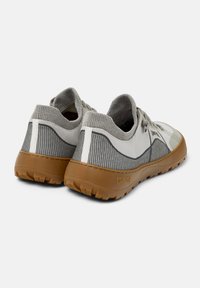 Baskets de sport gris et blanc avec une tige en maille, un tissu texturé, des lacets élastiques et une semelle extérieure en caoutchouc gomme avec un motif de treads détaillé.
