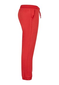 Pantalones de chándal rojos hechos de una tela suave, con una cinturilla elástica y cordón, bolsillos laterales y puños ajustados en los tobillos.