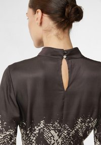 Dunkles satiniertes Kleid mit langen Ärmeln, das einen Knopfverschluss am Hinterhals und ein dezentes Druckmuster am Saum aufweist.