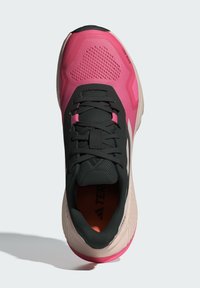 Zapatilla deportiva negra y rosa con parte superior texturizada, detalles de malla, cordones robustos y una suela acolchada con un acento rosa.