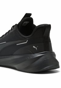 Chaussure de sport noire avec une tige texturée, un design élégant, des accents réfléchissants et une semelle rembourrée arborant un logo de marque sur le talon.