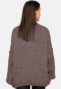 Pull en tricot oversize de couleur mauve pâle, présentant un motif en relief et des manches larges, avec un ourlet côtelé et un design dos ouvert.