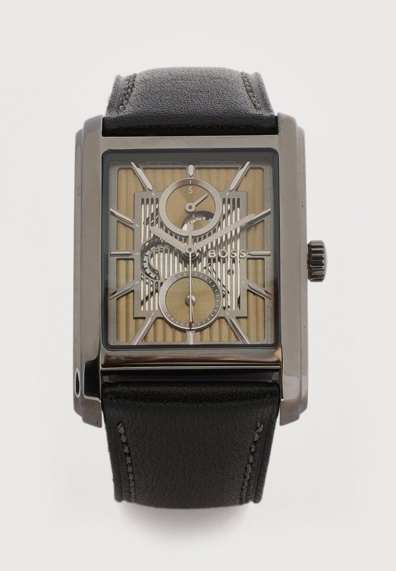 Ορθογώνιο ρολόι χειρός με μαύρο δερμάτινο λουράκι, ασημένια θήκη, μπεζ και ασημένιο καντράν, δύο υποκαντράν και ασημένιους δείκτες και σημάδια ώρας.