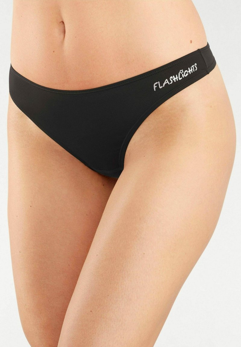 Schwarze Bikiniunterhose mit einem tief sitzenden Design. Glatte Textur, mit einem seitlichen Logo "FLASHLIGHTS" in Weiß. Einfacher und minimalistischer Stil.