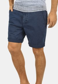 Shorts en coton bleu marine avec un ourlet roulé, dotés de poches latérales et d'une texture douce. Conçus pour un usage décontracté et un confort optimal.