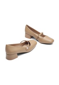 Le scarpe Mary Jane in pelle beige presentano una punta quadrata, un tacco basso a blocco, una cinturino alla caviglia e un accento decorativo in perle.