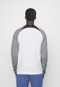 Sudadera con un cuerpo blanco y mangas en degradado gris, con detalles en negro en el cuello y el logo "LFC" en la parte posterior del cuello.