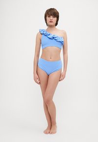 Světle modrý texturovaný dvoudílný bikini set. Vrchní díl má jedno rameno s volánkovým detailem; spodní díl je vysoký v pase. Jednoduchý design, bez vzorů.