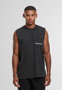 Maglietta nera senza maniche con colletto girocollo, con un piccolo logo bianco "Sunday Running Club" sul lato sinistro del petto, realizzata in un tessuto morbido.