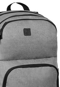 Mochila gris hecha de tela texturizada con acentos en negro, que presenta un logotipo de marca prominente, múltiples compartimentos con cremallera y correas acolchadas.