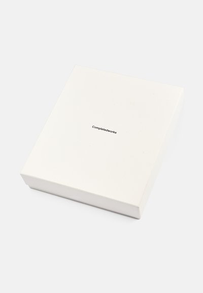Λευκό τετράγωνο κουτί με ματ φινίρισμα, που περιλαμβάνει το κείμενο "Completedworks" σε μικρή μαύρη γραμματοσειρά, κεντραρισμένο στην επάνω επιφάνεια.