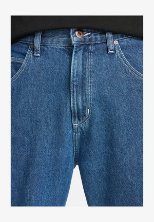 Jeans de mezclilla azul con un diseño de talle alto, botón de cobre y estilo estándar de cinco bolsillos con detalles de costura visibles.