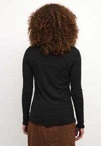 Black ribbed long-sleeve shirt with fitted design, round neckline, and ruffled cuffs. Visible stitching and a smooth texture.