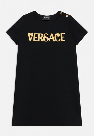Robe noire à manches courtes avec logo doré "VERSACE" sur la poitrine et deux boutons dorés sur l'épaule gauche, col rond.