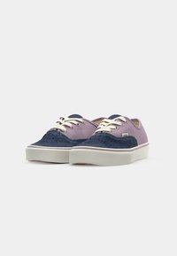 Purple and navy sneakers with textured fabric and smooth panels. Cream laces and a white sole. Low-top design with a rounded toe.