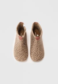 Et par beige slip-on tøfler med brune leopardprikker og brun indvendig foring på en hvid baggrund.