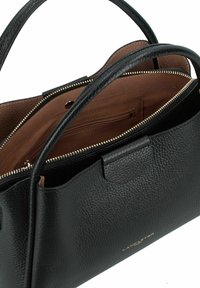 Borsa a mano in pelle nera con finitura testurizzata, chiusura con zip e interno marrone. Presenta due manici e una piccola tasca interna.
