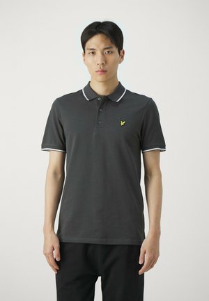 Polo shirt grigio scuro con colletto, patta con tre bottoni e rifiniture bianche. Presenta un piccolo logo giallo sul lato sinistro del petto. Texture liscia.