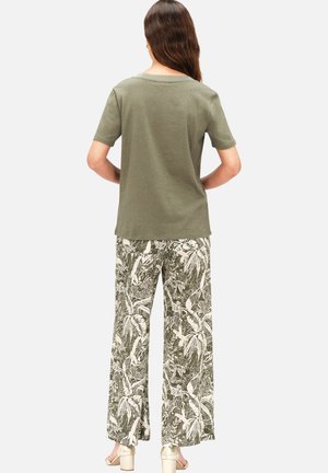 Olijfgroene t-shirt met korte mouwen, gecombineerd met wijde broek met een witte botanische print op een donkergroene achtergrond. Eenvoudig ontwerp.