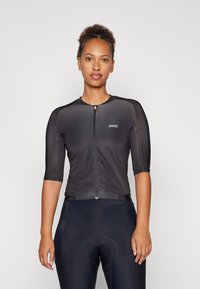 Schwarzes Radtrikot mit halben Ärmeln, Frontreißverschluss und gepolsterten Fahrradshorts. Hergestellt aus dehnbarem Stoff mit glatter Textur.