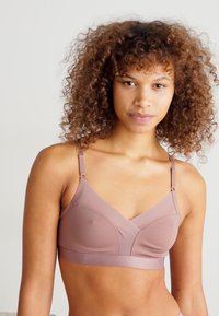 Soutien-gorge sans fil en mauve avec un tissu texturé, un design en V, des bretelles ajustables et une bande lisse. Construction douce et offrant un bon maintien.