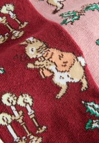 Knit sweater featuring a pattern of a light brown dog and candles on a red and pink background; soft texture with detailed, colorful designs.