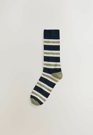 Ein einzelner marineblauer Socken mit weißen und olivgrünen horizontalen Streifen, olivgrüner Ferse und Zehen, flach auf einem hellen Hintergrund ausgelegt.