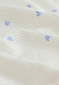 Tissu en coton avec une surface texturée, présentant un fond blanc et des motifs de cœurs bleu clair dispersés.