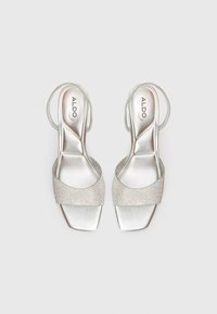 Sølv høye hælsandaler med firkantet tå, med en glitrende rem dekorert med rhinestones og et slingback-design.