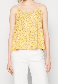Top de tirantes finos en color amarillo con flores, que presenta un corte holgado y pequeños patrones florales en blanco y rosa sobre una tela texturizada.