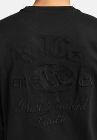 Zwarte longsleeve shirt met geborduurde tekst "RVCA" en een wereldontwerp. Heeft een detail "Past Present Future" in een vergelijkbare tonale borduurovereenkomst.