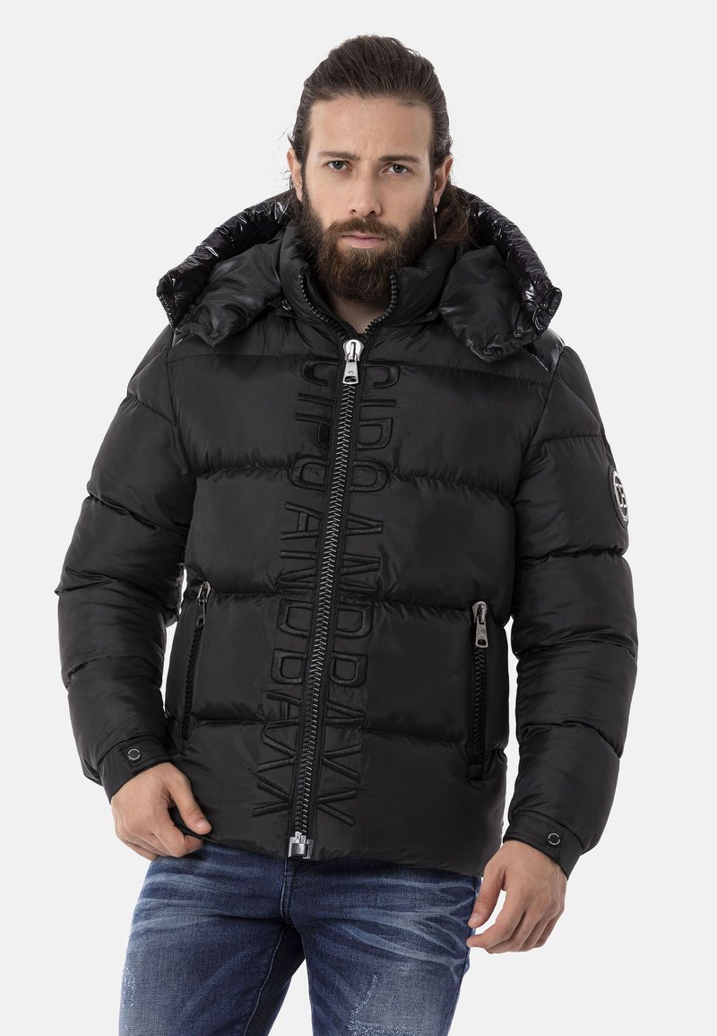 Schwarze Steppjacke mit hohem Kragen, Reißverschlüssen und gestickter Markenkennzeichnung. Hergestellt aus glänzendem, gestepptem Material mit Seitentaschen.