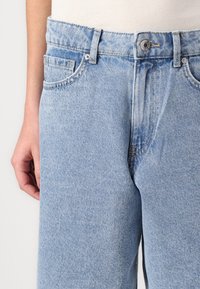 Light blue denim jeans with a straight cut, featuring five pockets, belt loops, and subtle fading around the thighs and waist.