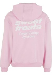 Pink hooded sweatshirt with white printed text reading "sweet treats" and "Candy's Loving Symphony" on the back, featuring ribbed cuffs.