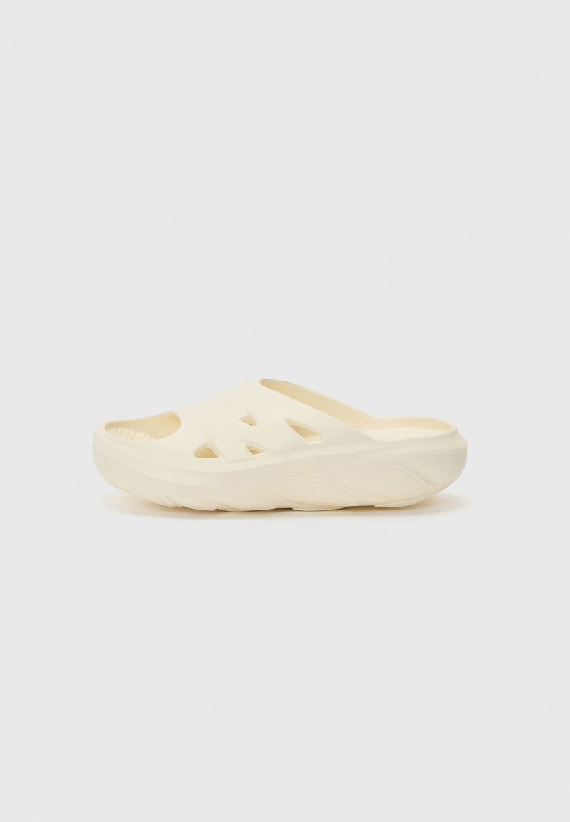 Cream-colored slide sandal with an open toe, three side cutouts, textured insole, and a thick, curved sole for comfort.