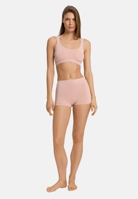 Ljust rosa bralette och shorts-set, tillverkat av mjukt tyg. Har en enkel design med en ärmlös topp och mid-rise shorts. Slät textur.
