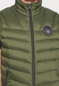 Groene gewatteerde vest met verticale stiksels, hoge kraag, ritssluiting aan de voorkant en logopatch op de linkerborst. Is voorzien van ritszakken.